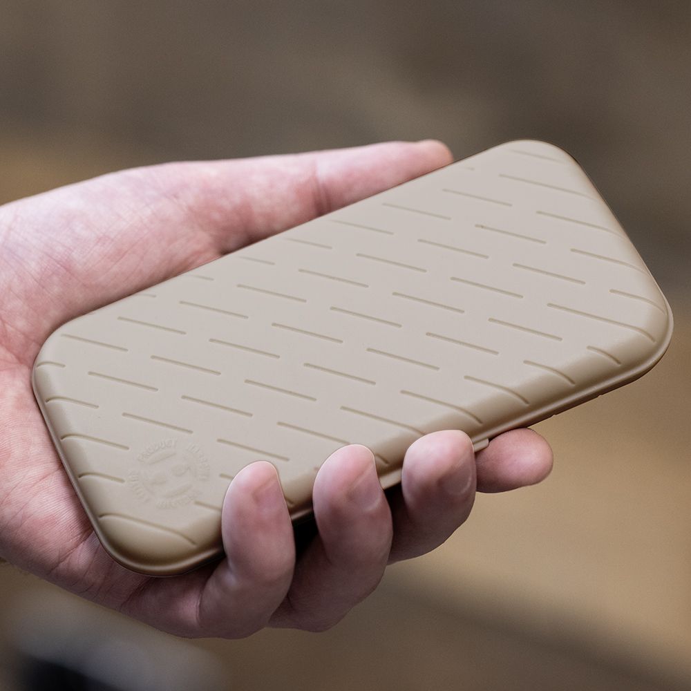 Eine Hand hält ein schlankes, steingraues Etui mit einem dezenten Muster. Das Etui wirkt stabil und ist wahrscheinlich für Dartzubehör gedacht.