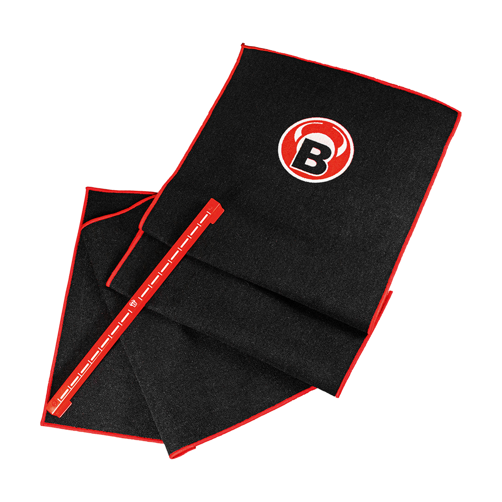 Das Bild zeigt das Bulls Oky System Set, bestehend aus einem schwarzen Teppich mit rotem Rand und einem Metall Oche. Auf dem Teppich ist ein rundes Logo mit einem "B" zu sehen.