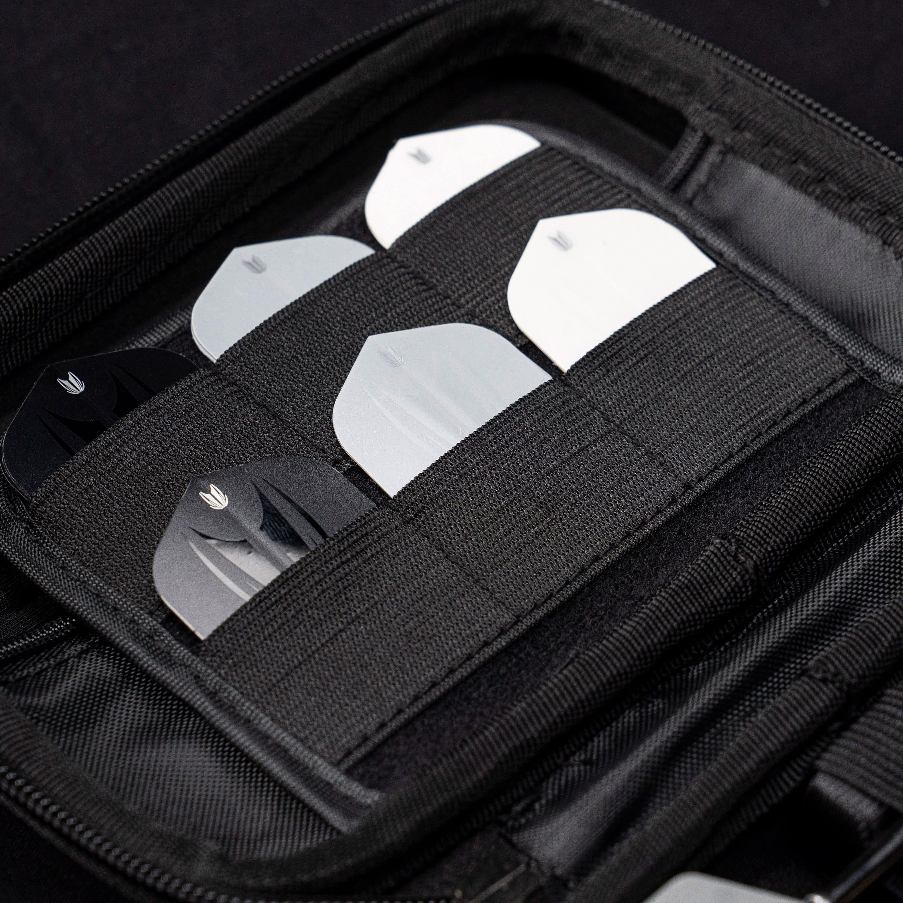 Takoma Ghost Series Chris Dobey dart case Das Bild zeigt das Target Takoma Bolide Dartcase, in dem mehrere Dart-Flights ordentlich in elastischen Halterungen verstaut sind. Das Case ist schwarz und bietet sicheren Schutz für das Dartzubehör.