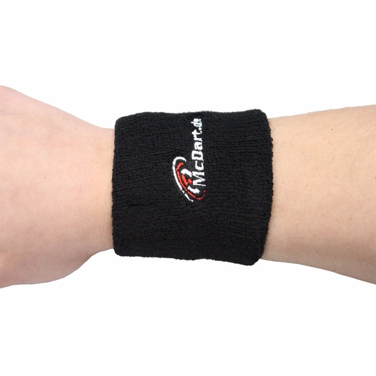 1690_2 Auf dem Bild ist ein schwarzes Schweißband mit der Aufschrift "McDart" zu sehen. Das Schweißband wird am Handgelenk getragen.