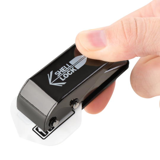 Das Bild zeigt das Produkt "L-Style One80 Shell Lock Punch Flightlocher", das in einer Hand gehalten wird. Mit diesem Werkzeug wird ein Loch in ein Dartflight gestochen.